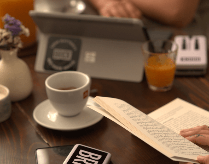 Telefonunu bir tuğla ile şarj ederken kitap okuyan kadın